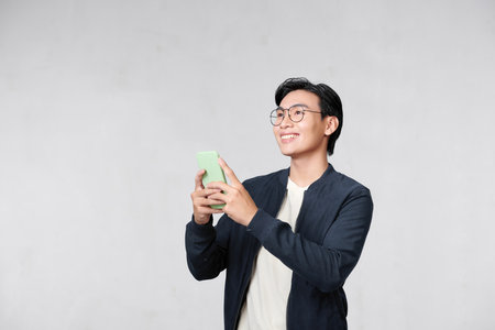 Portrait of cheerful man using cellphone and smiling, reading good news message, enjoying mobile applicationの写真素材