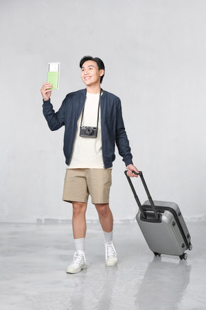 Portrait of happy young guy holding passport and boarding pass against white backgroundの写真素材