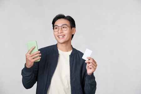 Young asian man buying with the mobile with a credit cardの写真素材
