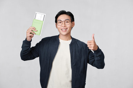 Man smiling, looking at camera and holding tickets with passportの写真素材