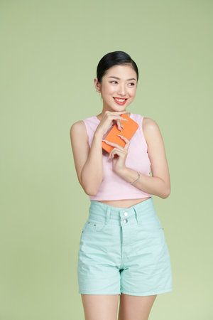 Asian happy beautiful women blogger smiling and holding smartphone isolated on colour backgroundの写真素材