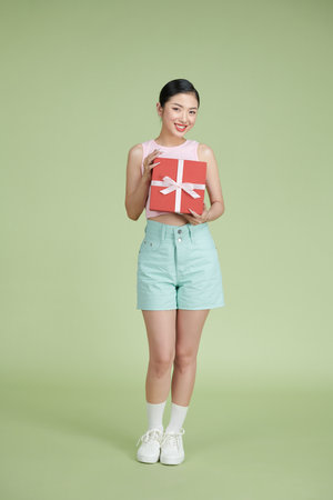 Photo portrait of excited woman holding gift box in two handsの写真素材