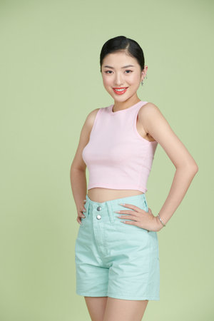 happy smiling young woman with hands on hips posing over green backgroundの写真素材