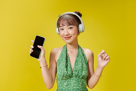 woman posing isolated over yellow background listening music with headphones dancing singing.の写真素材