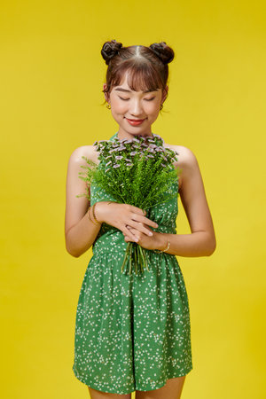 Happy woman in polka dot outfit laughing and holding flowers.の写真素材