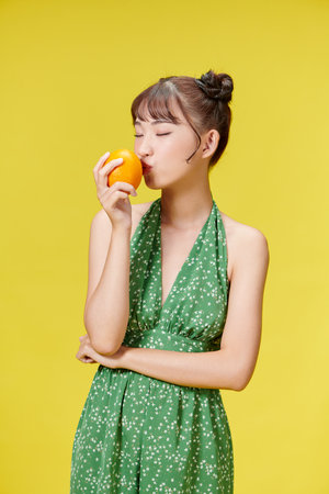 Portrait of pretty young woman holding juicy delicious orangeの写真素材