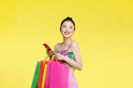 Beautiful asian woman are holding shopping bags and mobile phone with face happilyの写真素材