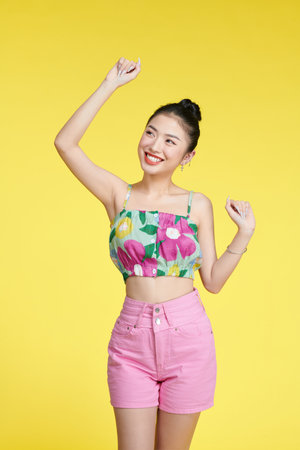 Photo of attractive joyful young woman raise hands dance smile isolated on yellowの写真素材