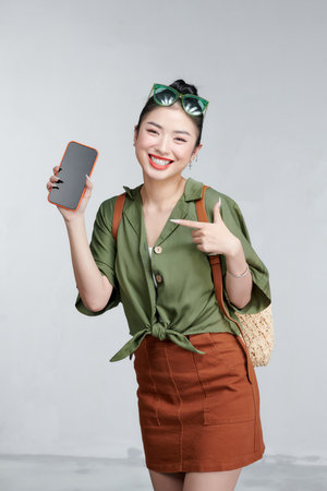 Beautiful woman showing smartphone and pointing something in travel summer trip in vacationの写真素材