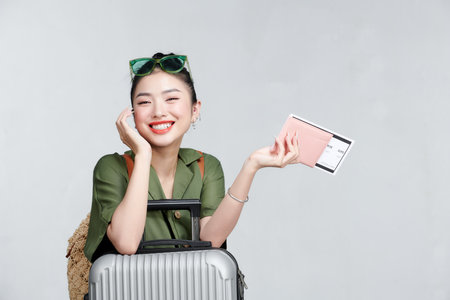 Young woman isolated on gray teen style traveler sitting on suitcaseの写真素材
