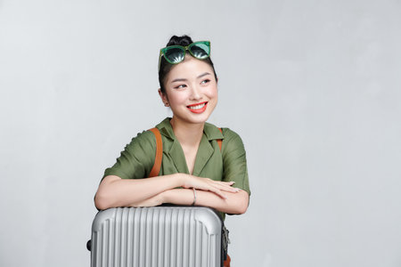 Woman traveler with suitcase on gray backgroundの写真素材