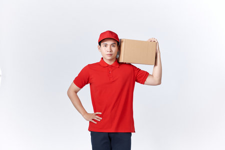 Young asian man holding delivery package smiling happy and positiveの写真素材