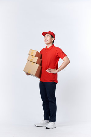 Young man holding delivery package looking positive and happy standing and smilingの写真素材