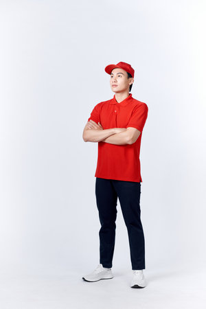 Professional smiling confident male employee in cap, t-shirt courier dealer holding hands crossed foldedの写真素材