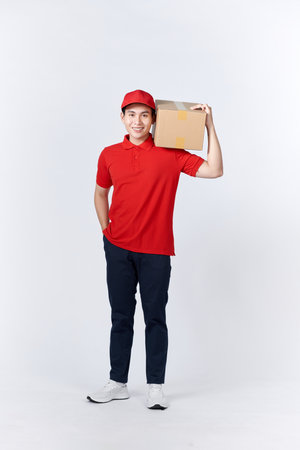 Young man holding delivery package looking positive and happy standing and smilingの写真素材