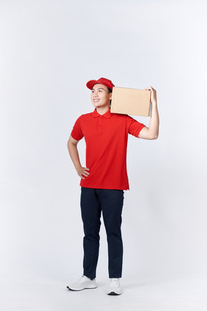 Young man holding delivery package looking positive and happy standing and smilingの写真素材