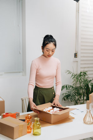 Young woman, owener of small business packing product in boxes, preparing it for delivery.の写真素材