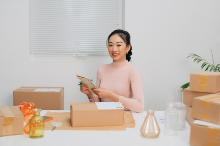 Young beautiful woman checking a parcel, with smiling look happy with her jobの写真素材