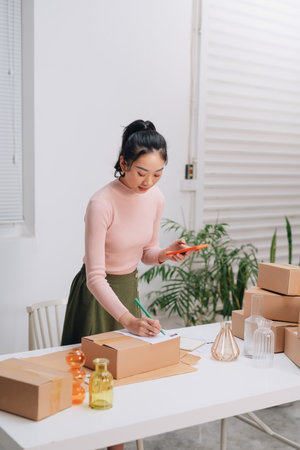 Female online store preparing an order for shipping in a warehouseの写真素材