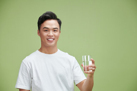 young man holds a glass of pure waterの写真素材