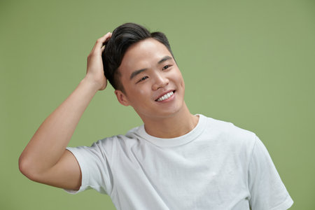 Young man smiling confident touching hair with hand up gesture, posing attractive and fashionableの写真素材