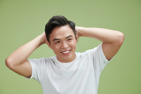 Happy handsome smiling man touching his hairの写真素材