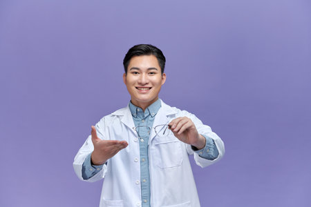 smiling ophthalmologist with hand in pocket holding eyeglassesの写真素材