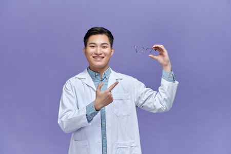 Male optometrist holding eyeglasses in clinicの写真素材