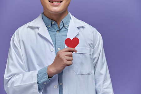 male doctor with stethoscope holding heart, on light backgroundの写真素材