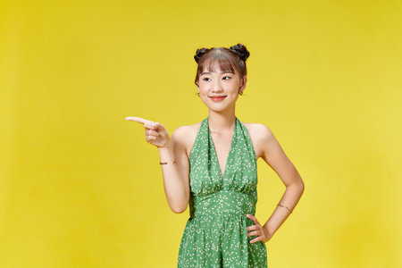 young Asian woman posing on yellow backgroundの写真素材