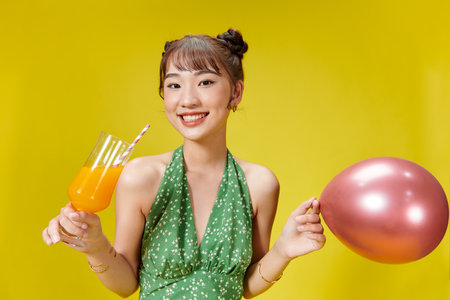 Happy Asian woman in summer casual clothes with a glass of fresh fruit juice drinkの写真素材