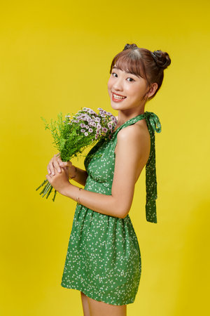 Photo of nice young asian lady hold flowers wear summer clothes isolated on yellow backgroundの写真素材