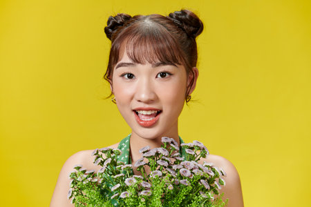 Charming asian woman in green summer jumpsuit with wildflowers in her hands smilingの写真素材