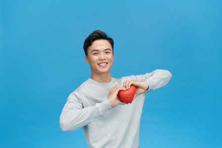 man holding heart smiling with a happy and cool smile on face.