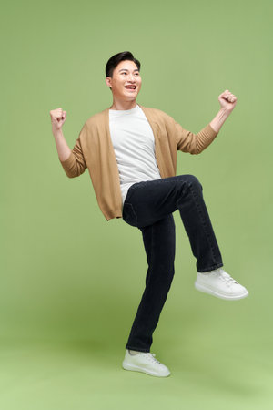 Full length of a satisfied young man celebrating success isolated over green backgroundの写真素材