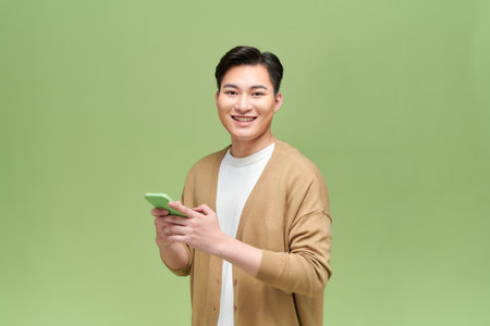 Happy asian young man using smart phone cellphone for callsの写真素材
