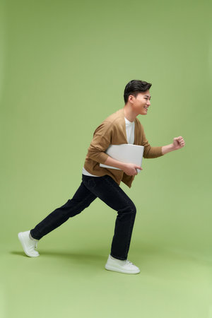 Full length image of young Asian businessman on green backgroundの写真素材