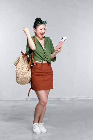Traveler tourist asian woman hold passport tickets doing winner gesture isolated on white backgroundの写真素材