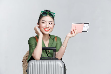 Image of excited young pretty woman tourist with suitcase holding passport with ticketsの写真素材