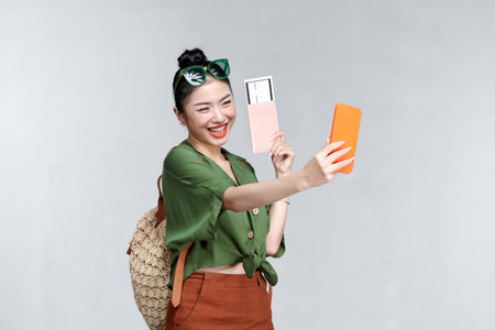 Happy Traveler woman with passport and boarding tickets take a selfie by smartphoneの写真素材