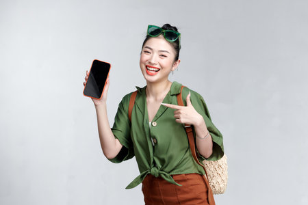 Young woman showing smartphone for presenting and pointing something on a travel summer tripの写真素材