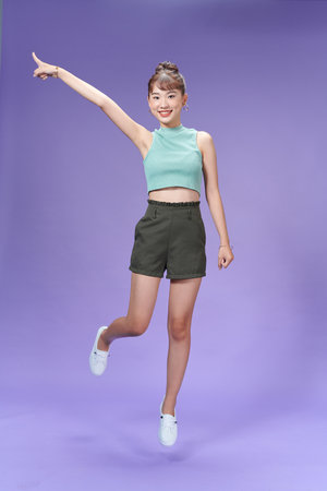 Portrait beautiful woman showing a happy expression and point up on a purple backgroundの写真素材