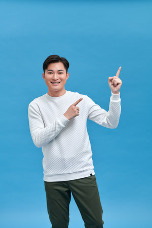 Portrait of a successful cheerful young man pointing and presenting something with fingerの写真素材