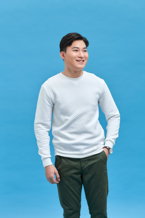 charming cheerful positive young man hold hands pockets isolated on blue backgroundの写真素材