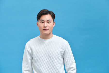 Portrait of good looking asian man over blue background.の写真素材