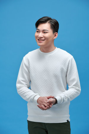 young happy asian man standing with arms crossed over blue wallの写真素材