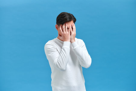 Asian young man looks upset and squeezing their heads with hands from a headacheの写真素材