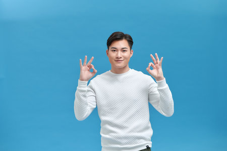 Young asian man showing ok hand sign and smilingの写真素材