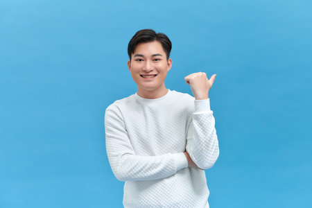 man smiling with happy face looking and pointing to the side with thumb up.の写真素材