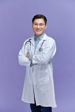 portrait of friendly Asian doctor man over purple smiling to cameraの写真素材